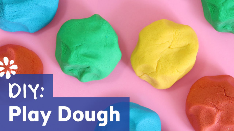 Mounds of colorful home made play dough on a pink background with the words "DIY: Play Dough"