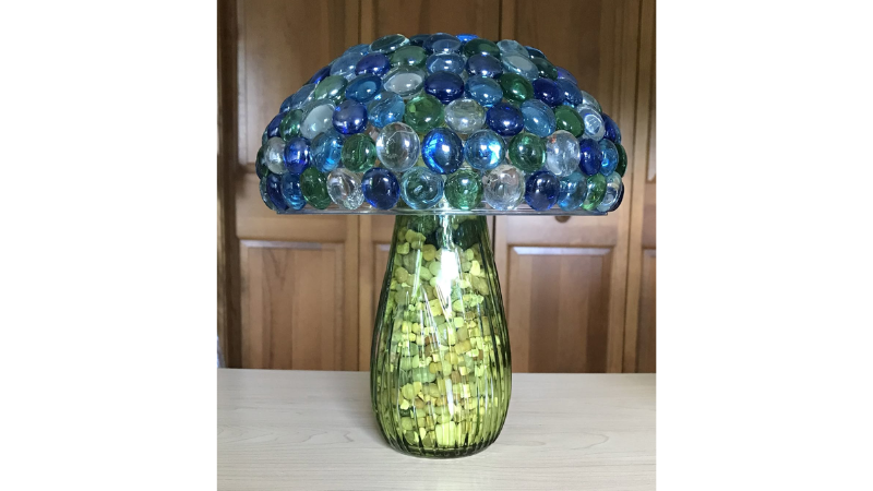 a glass bowl fixed upside down to the top of a narrow spouted vase with glass stones glued all over to make a mushroom shape
