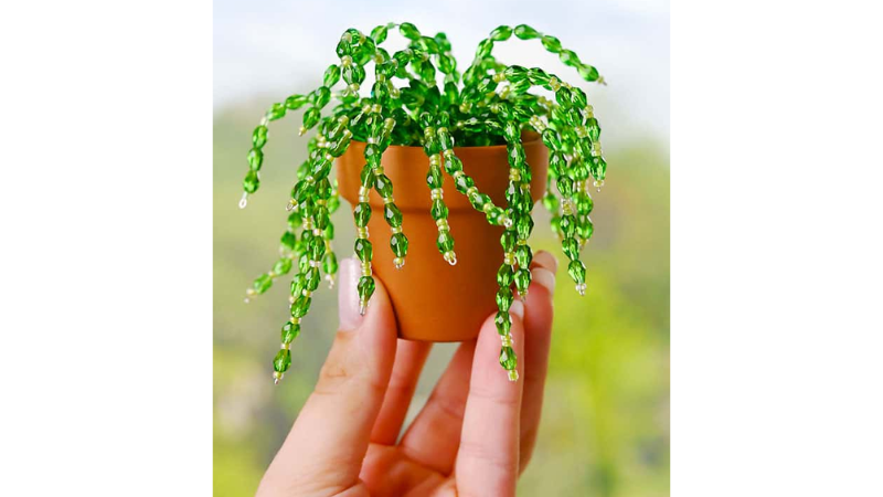 fake plant in a mini terracotta pot. plant is made of wire and small green beads